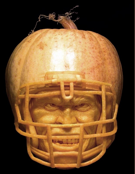 Pumpkin carved to look like it's wearing an American Football helmet