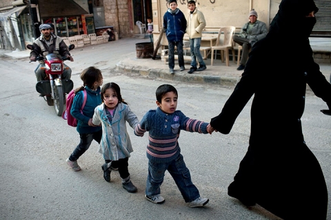 Một phụ nữ dắt trẻ em đi trên đường phố ở Kafar Taharim, Syria.