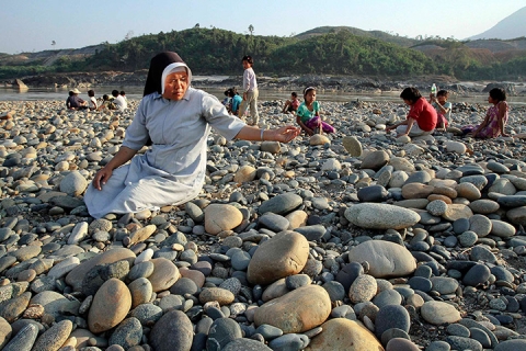 Một nữ tu sĩ và các học sinh trong tu viện nhặt đá để xây tường quanh tu viện ở Myitsone, Myanmar.