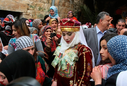 Cô dâu người Palestin Mhaha Salam được gắn tiền tiền giấy lên váy như một món quà truyền thống. Đám cưới diễn ra ở Deir Estia, Palestin.