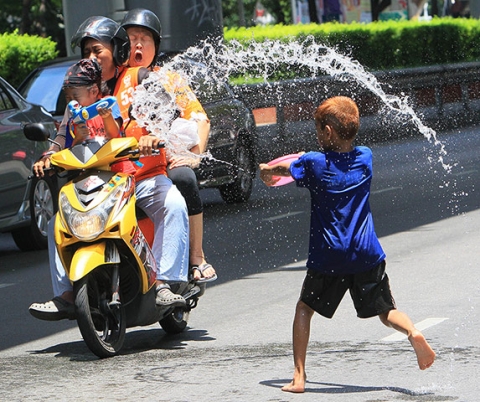 Một cậu bé té nước vào người đi trên phố trong Lễ hội té nước Songkran đón năm mới ở Bangkok, Thái Lan.