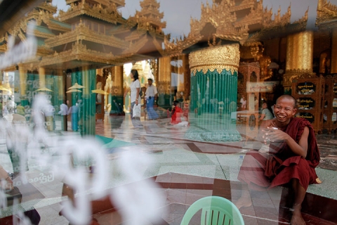 Một nhà sư cười sảng khoái khi ngồi sau hòm cung đức trong chùa Shwedagon ở Rangoon, Myanmar.