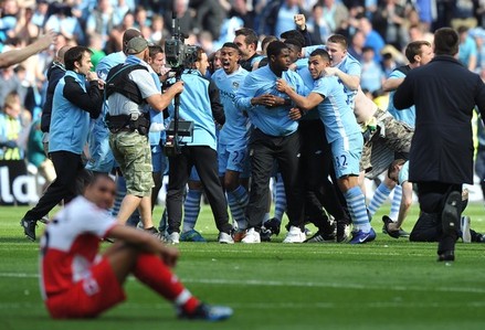 Manchester City's players and supporters celebrate on the pitch after their 3-2 victory over Queens Park Rangers in the English Premier League football match between Manchester City and Queens Park Rangers at The Etihad stadium in Manchester,...