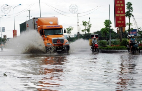 Một người đi xe máy bị nước bắn lên ướt như chuột