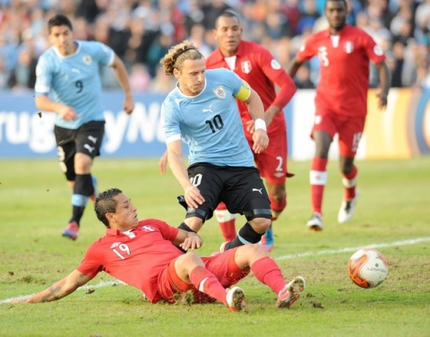 Uruguayan forward Diego Forlan (C) is marked by Peruvian player Yoshimar Yotun Flores (bottom) during their Brazil 2014 FIFA World Cup South American qualifier match at the Centenario stadium in Montevideo on June 10, 2012. Uruguay won 4-2.