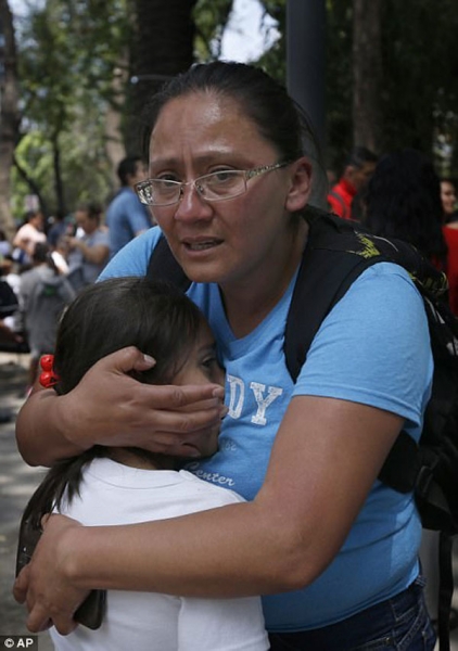 Một bà mẹ đang đứng ngoài trường học và trấn an con gái nhỏ trước màn thảm họa khủng khiếp.