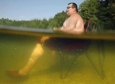 Nắng nóng kinh hoàng ở Mỹ hồi tháng 7/2011 ảnh hưởng đến cuộc sống của người dân. Trên ảnh là một người đàn ông ở Gortham, Maine đặt ghế dưới nước và ngồi xuống ghế mong giảm nhiệt.