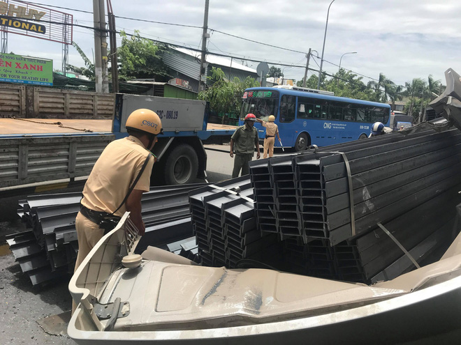 Hàng trăm thanh đà thép bị rơi, hất phần cabin container và tài xế bay xuống đường - Ảnh 1.