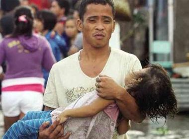 Một người đàn ông bế trên tay con gái bé nhỏ xấu số của mình sau khi siêu bão hủy diệt thành phố Tacloban.