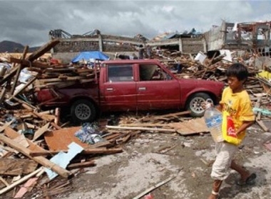  Một cậu bé cầm bình đi tìm nước uống giữa đống đổ nát tại thành phố Tacloban