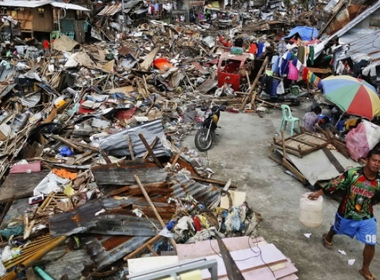 Một người dân xách nước sạch ngang qua khu vực đã bị bão cày nát ở thành phố Tacloban Ảnh: Reuters