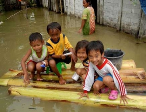  Trẻ em chơi trên bè làm bằng thân cây chuối trước một ngôi nhà bị ngập lụt tại ngôi làng Truni ở Indonesia.