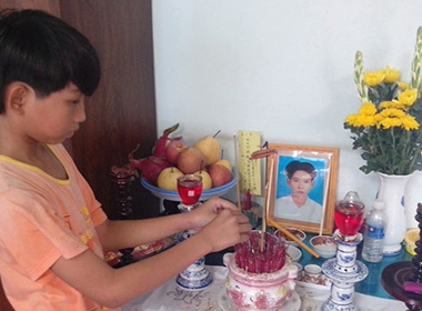 Con trai anh Nguyễn Văn Đức bên di ảnh của cha