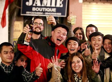 Người nước ngoài bật đồ uống chia sẻ niềm vui cùng giới trẻ Việt Nam ngoài đường phố. Ảnh: Lê Hiếu.