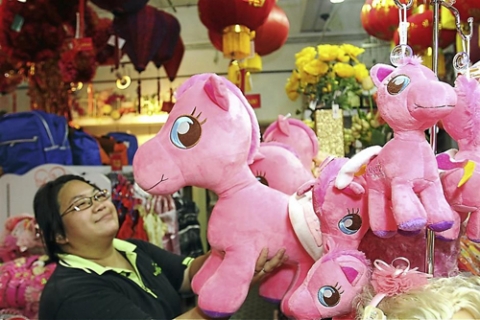 Một khách hàng chọn mua con thú hình ngựa tại một khu chợ ở Kualar Lumpur, Malaysia, trước Tết Giáp Ngọ