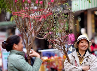 Nụ cười tươi của hai người phụ nữ bán nhành hoa đào trên đường phố thủ đô Hà Nội - Ảnh: EPA