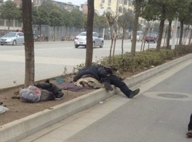 Hình ảnh người đàn ông say rượu ngủ gục trên dải phân cách giữa đường.