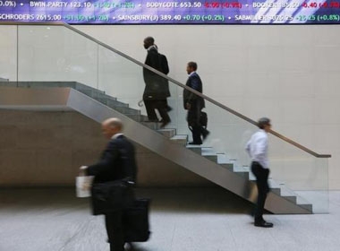 Người đi bộ qua một hội đồng quản trị thông tin điện tử tại thị trường chứng khoán London trong thành phố London 11/10/ 2013.