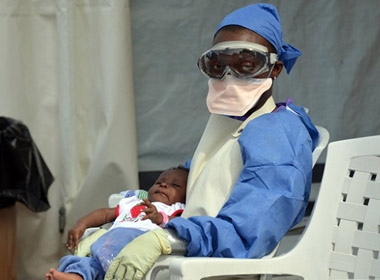 Một nhân viên y tế ở Liberia bế một trẻ bị nhiễm Ebola.