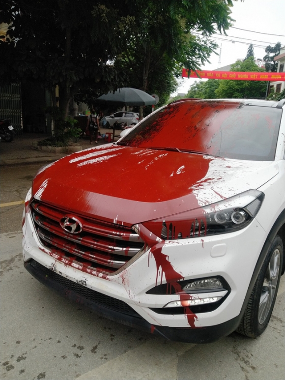 Hình ảnh chiếc ô tô trắng bị đổ sơn đỏ khắp thân xe khiến dân mạng bàn luận xôn xao ngày cuối tuần